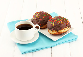 Tasty donuts on color plate on light wooden background