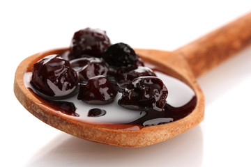 tasty berry jam in wooden spoon, isolated on white
