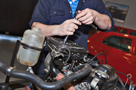Man holding a spanner over a car engine