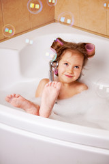 Little girl  in curlers in the bathtub