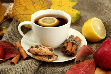 cup of hot tea and autumn leaves, on burlap background