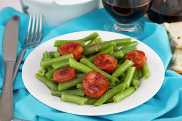 boiled green beans with fried sausages and glass of red wine