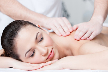 Fototapeta na wymiar Woman receives relaxing body massage at spa salon