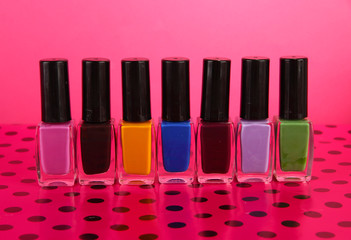 bright nail polishes on table on pink background