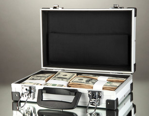 Suitcase with 100 dollar bills on grey background