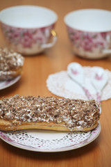 Eclairs for a couple on a wooden table with pink cups