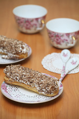 Eclairs for a couple on a wooden table with pink cups