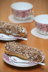 Eclairs for a couple on a wooden table with pink cups
