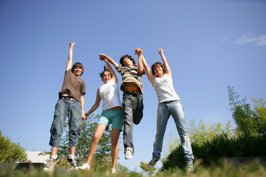 Group of teenagers holding hands and jumping in the air