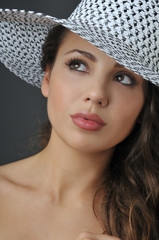 Beautiful young brunette girl in the studio wearing white hat