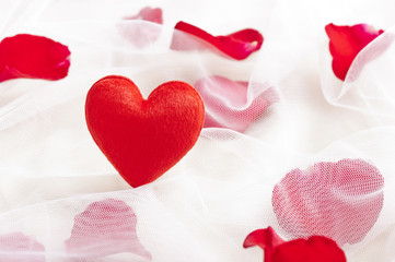 Red heart on wedding veil with rose petals