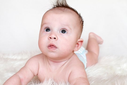 The surprised baby lies on a stomach on a fur plaid (3,5 months)