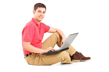 Young man sitting on the floor and working on a laptop