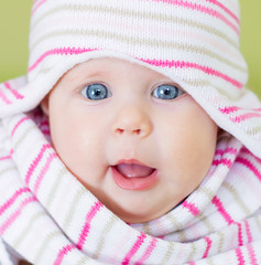 Cute smiling baby portrait with blue eyes in knit hat and scarf