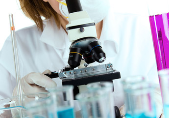 Detail of modern microscope with female researcher in a lab