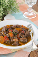 stew of beef with vegetables and prunes in a plate, vertical