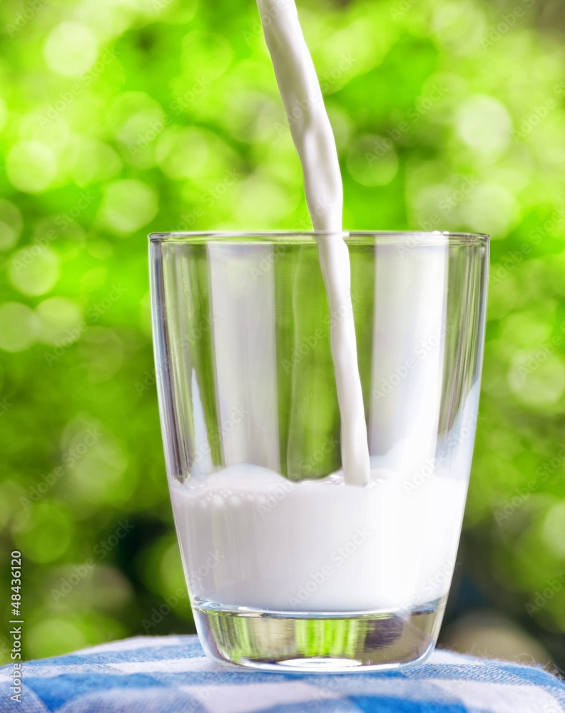 Wall mural Glass of milk on nature background