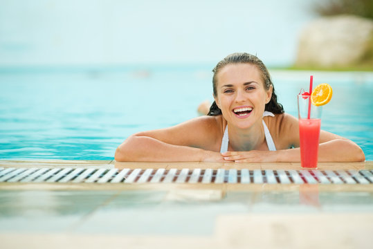 Smiling Young Woman Relaxing In Pool With Cocktail