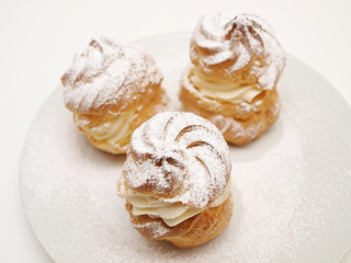 Obraz na płótnie Canvas Choux pastry buns, filled with whipped cream, on a plate