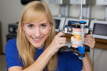 Smiling dental technician with articulator