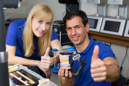 Two dental technicians with articulator showing thumbs up