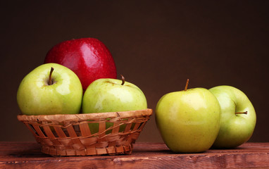 juicy sweet apples in basket on wooden table on brown