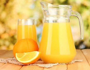 Full glass and jug of orange juice and oranges