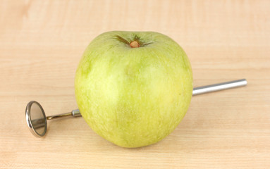 Green apple and dental tool on wooden background