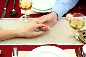 Obraz na płótnie Canvas hands of romantic couple over a restaurant table
