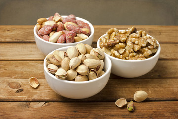 Assorted nuts in dishes on wooden table
