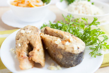 fried fish slices on a plate with greens