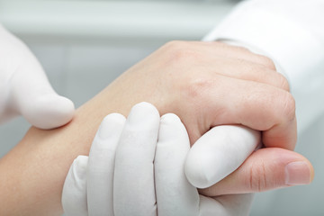 Doctor hand touches and holds the hand of the patient