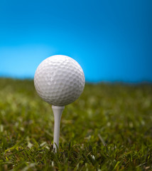 Golf ball on green grass over a blue background 