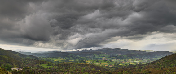 Dark stormy clouds over a green valley in Cantabria Spain © herraez
