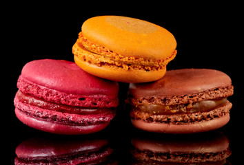Three colorful macarons on black background