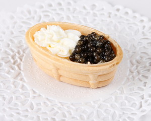 Canape with cream cheese and caviar on a white paper