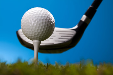 Golf ball on green grass over a blue background 