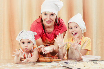 Mother with two daughters baking bread.