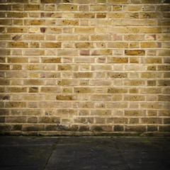 Grunge brick wall and dark stone floor with vignette