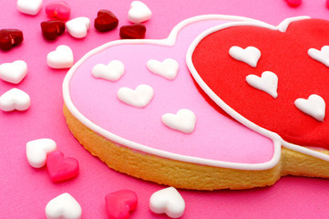 Heart shaped Valentines Day cookies and candies on pink paper