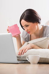 A young woman lying on the floor in front of her laptop and chat