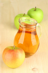 Full jug of apple juice and apple on wooden background