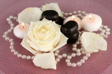 spa stones with flower and candles in water on plate