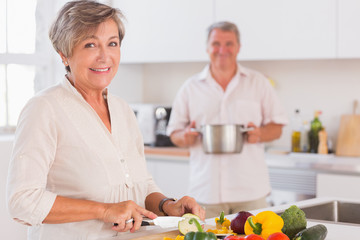 Old couple smiling preparing food