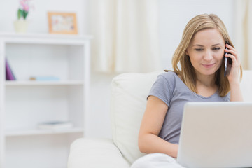 Fototapeta premium Casual woman using laptop and cellphone at home