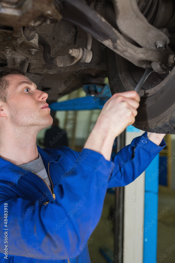Poster man adjusting car tire with spanner