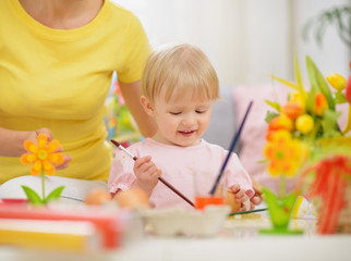 Obraz premium Happy mother and baby making Easter decorations