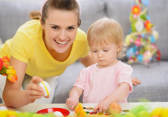 Obraz premium Happy mother and baby making Easter decorations