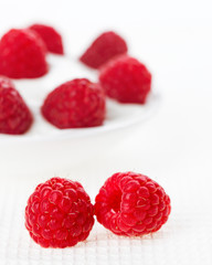 Still life with pair of raspberry on white linen table cloth, co