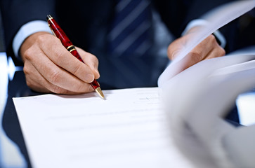 Close up of businessman signing a contract.